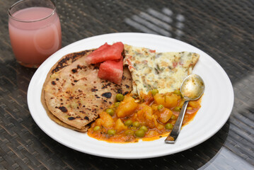aloo roti tandoori roti or paratha, parantha with spicy  jeera / masala aloo mutter or aloo ki sabzi potato curry traditional Indian breakfast recipe Jaipur Rajasthan, India.  Made with whole wheat 