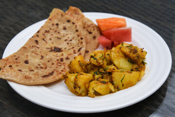 aloo roti tandoori roti or paratha, parantha with spicy  jeera / masala aloo mutter or aloo ki sabzi potato curry traditional Indian breakfast recipe Jaipur Rajasthan, India.  Made with whole wheat 