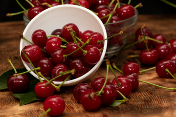 Red berries of a cherry in a white ceramic bowl. On a wooden background. A lot of berries. Summer.