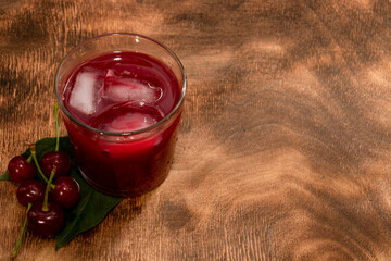 Red cocktail. Cherry juice with ice. Cherry leaves and cherry berries. The summer aroma of coolness in a glass. Juccy.