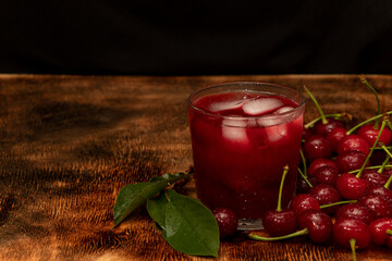 Red cocktail. Cherry juice with ice. Cherry leaves and cherry berries. The summer aroma of coolness in a glass. Juccy.