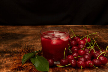 Red cocktail. Cherry juice with ice. Cherry leaves and cherry berries. The summer aroma of coolness in a glass. Juccy.