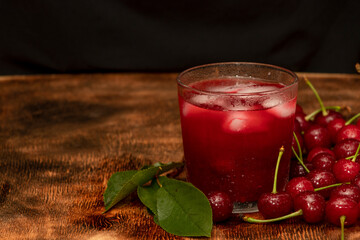 Red cocktail. Cherry juice with ice. Cherry leaves and cherry berries. The summer aroma of coolness in a glass. Juccy.