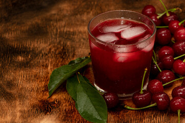 Red cocktail. Cherry juice with ice. Cherry leaves and cherry berries. The summer aroma of coolness in a glass. Juccy.