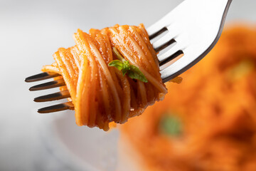 Close up of fork with rolled  Spaghetti and basil.