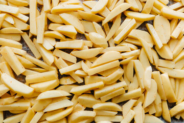 Sliced potatoes are laid out on a baking sheet and ready to be baked.