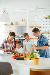 Mother and father making breakfast with sons. Young family preparing delicious food in kitchen.