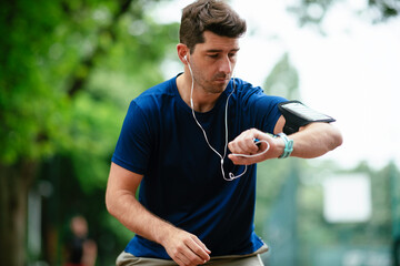 Young man checking his heart rate during work out. Young man exercising on athletics track