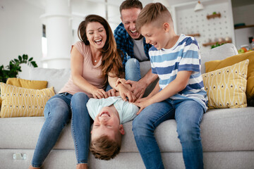 Young family enjoying at home. Happy parents with sons having fun.