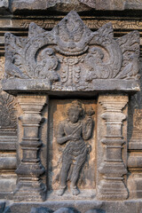 Wall carvings on stone at Prambanan hindu temples. Figure alone between two columns. Good spirit above it. Temples located close to the city of Yogyakarta, island of Java, Indonesia, Southeast Asia