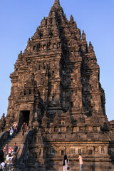 Indonesia; July 2019: Vertical picture of a building at the Prambanan complex temples. Local and international tourists climbing the stairs and taking pictures. Warm light. Yogyakarta, Java, Indonesia