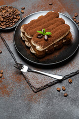 Classic tiramisu dessert on ceramic plate on concrete background