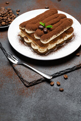 Classic tiramisu dessert on ceramic plate on concrete background