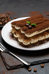 Classic tiramisu dessert on ceramic plate on concrete background