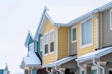Townhome exterior with snowy gable valley roof against overcast sky in winter