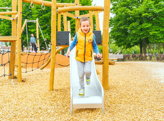 Selective focus. The boy climbing and sliding on slide in the playground. Happy children playing...