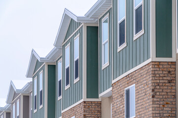 Vertical siding and stone brick wall at the townhomes upper storey against sky