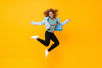 Fototapeta na wymiar Happy energetic smiling young African-American woman jumping isolated on yellow background