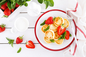 Cheese pancakes, fritters or syrniki with fresh strawberry and yogurt. Healthy and tasty breakfast