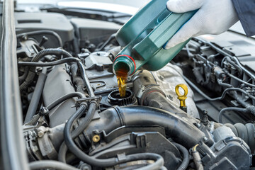mechanic pouring oil to car engine. auto motor service.