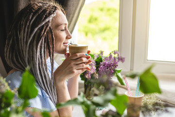 A cute young woman is enjoying an aromatic coffee on a sunny summer morning. Concept of a dreamy mood, a cozy atmosphere and a pleasant start to the day - Powered by Adobe