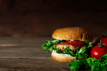 Fresh tasty chicken burger, tomato and lettuce on a wooden table
