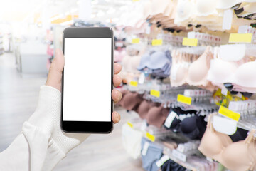 Woman hand use mobile smart phone to shopping online with blurry background of bra and lingerie in women underwear department