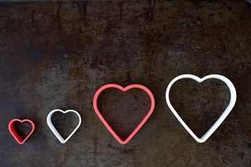 symbol of a family of two adults and two children in the form of four cutters hearts on dark background