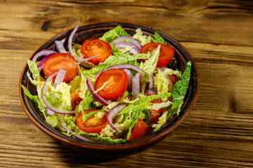 Healthy salad with savoy cabbage, cherry tomato, red onion and olive oil on wooden table