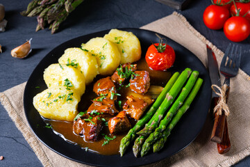 dumplings with beef goulash and green asparagus