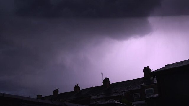 Lightning flashes over town houses in city of Manchester forceful nature UK 4K