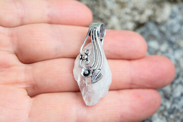 Natural crystal quartz gemstone with silver decoration pendant on female hand