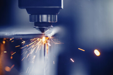 Laser CNC cutting of metal with light spark, modern industrial technology. Blue color steel tool