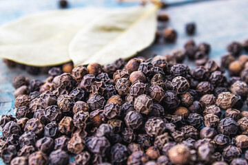 Black pepper and bay leaves are scattered on blue boards.