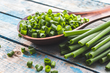Sliced green onion rings in a wooden spoon on a background of old blue boards.