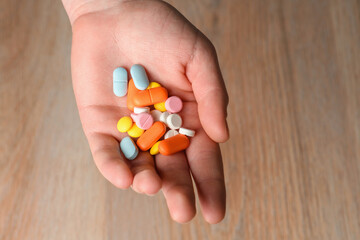 Several colored tablets in hand close-up. Concept of assistance in case of illness. Help with viral infection.