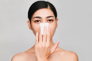 Young beautiful asian woman with clean, fresh and bright skin,holding Cotton swab with positive emotional,isolated on gray background,Beauty Cosmetics and Facial treatment Concept