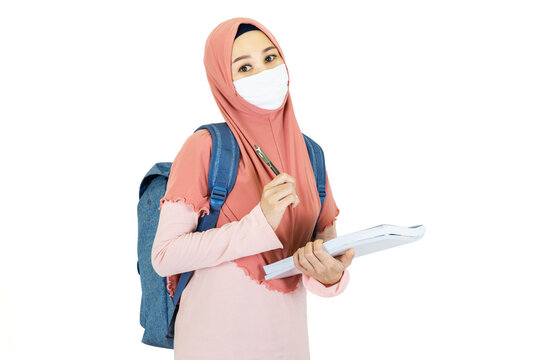 beautiful young muslim asian woman with traditional dress wearing medical face mask  to go to school Under the outbreak of the virus isolated on white background,health care concept