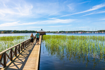 Naklejka premium Young couple walking on a jetty in a lake