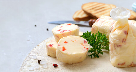 Butter with with pieces of sweet pepper for sandwiches and steak. Portion of Herb Butter sliced on a wooden board. Homemade italian food. Selective focus.