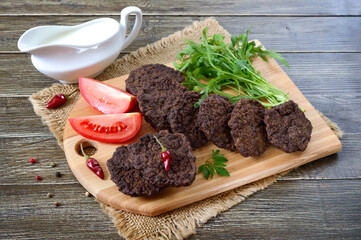 Tasty homemade liver cutlets stacked on a wooden board.