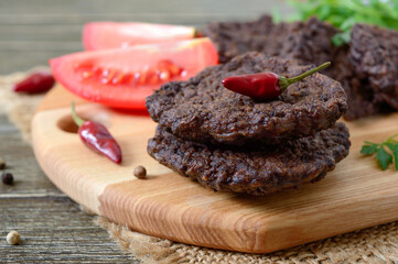 Tasty homemade liver cutlets stacked on a wooden board. Selective focus