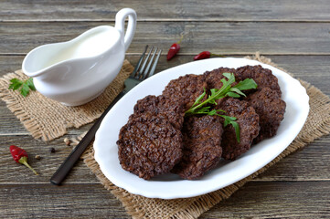 Tasty homemade liver cutlets on a plate and white sauce.