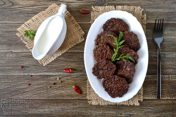 Tasty homemade liver cutlets on a plate and white sauce. The top view