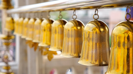beautiful golden traditional Buddhist bells waved by wind hang on long silver pipe against blurry...