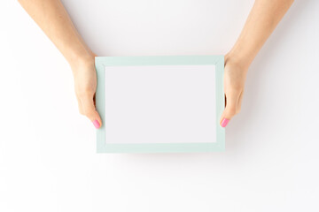 Woman’s hands showing blank photo frame isolated on white background. Mockup