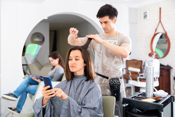 Young man hairdresser working with female client