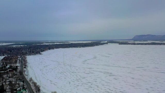 drone overlooking frozen river and coastline in winter time