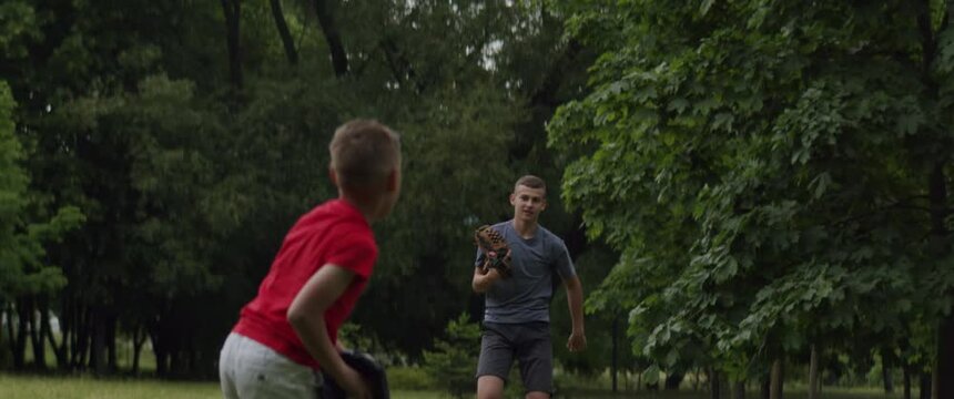 MED Two brothers or friends playing baseball catch in the park. Family time spent together. Shot with 2x Anamorphic lens