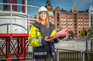 female apprentice holding a clipboard in front of city background